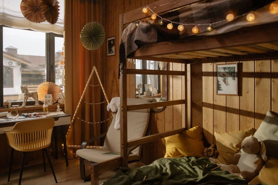 A wooden bunk bed with string lights in a cozy child's bedroom