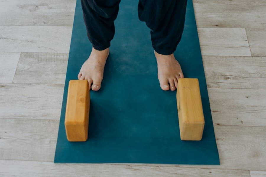 Bare feet on a teal yoga mat beside two cork yoga blocks