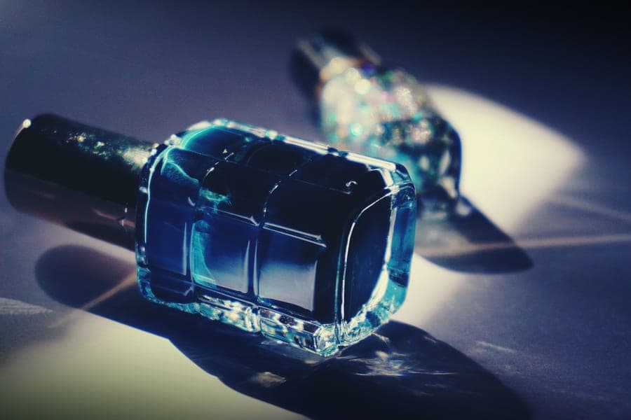 A blue glass nail polish bottle lying on its side under dramatic light